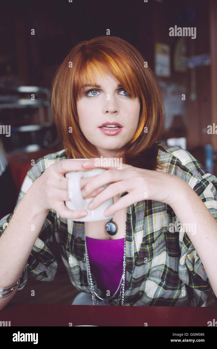 Caucasian woman drinking coffee in cafe Stock Photo