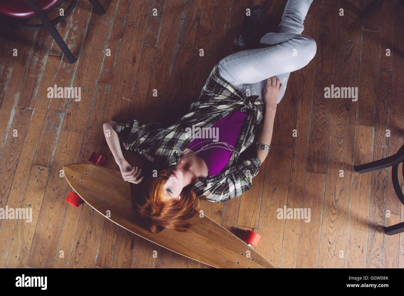 Caucasian woman laying on floor with skateboard Stock Photo