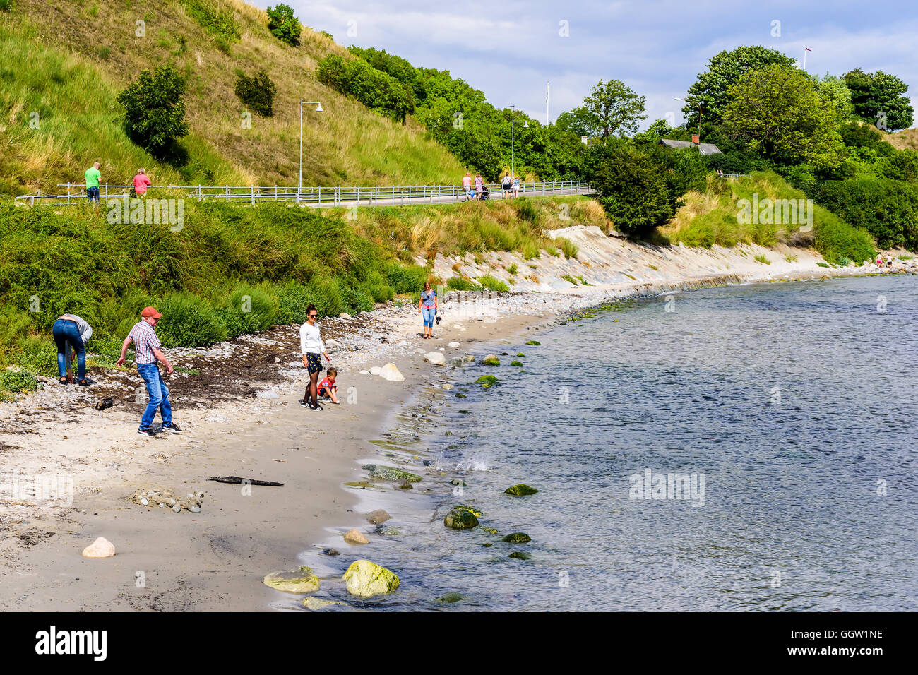 Kaseberga, Sweden - August 1, 2016: People walking and throwing stones at the beach. Real life situation. Stock Photo