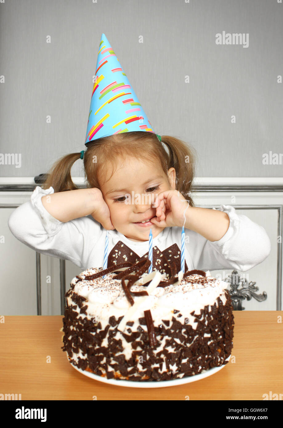 Portrait of funny little girl with birthday hat and cake Stock Photo