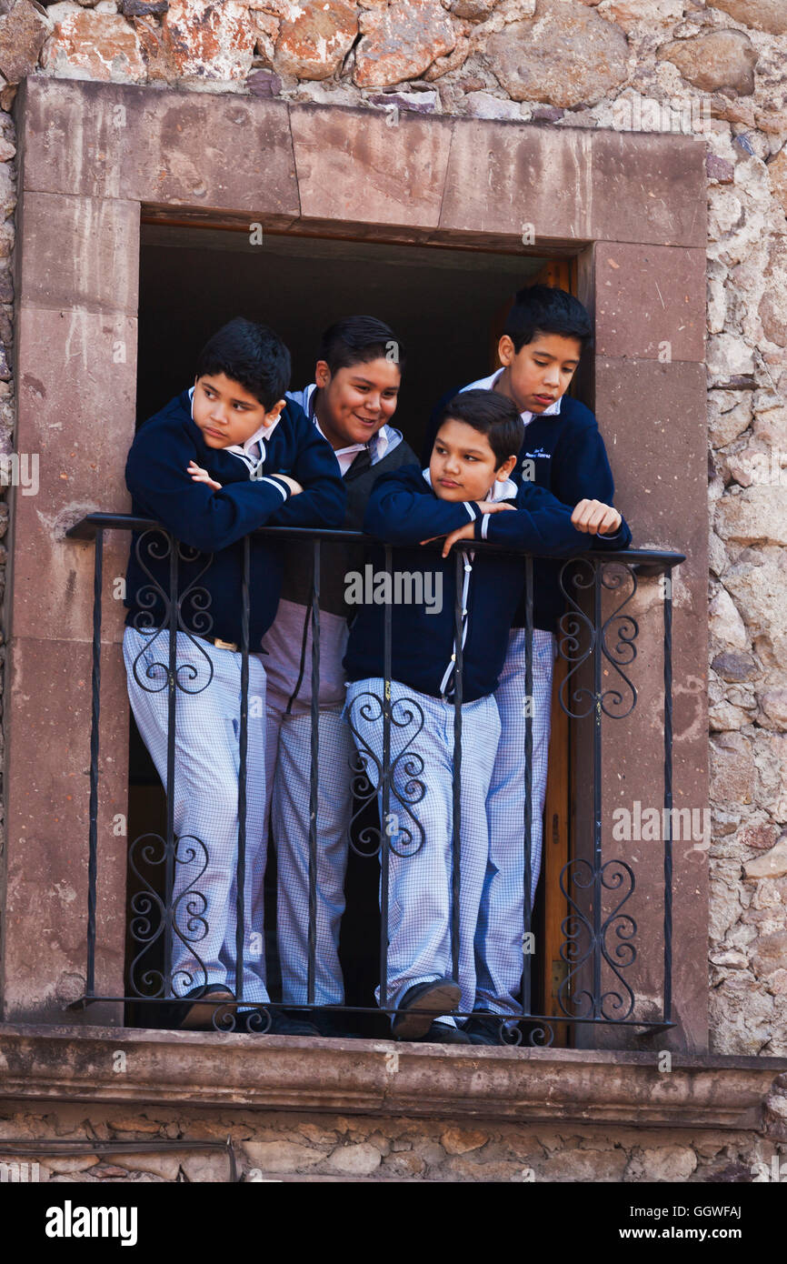 School children watch the parade celebrating DAY OF THE REVOLUTION on November 20th each year - SAN MIGUEL DE ALLENDE, MEXICO Stock Photo