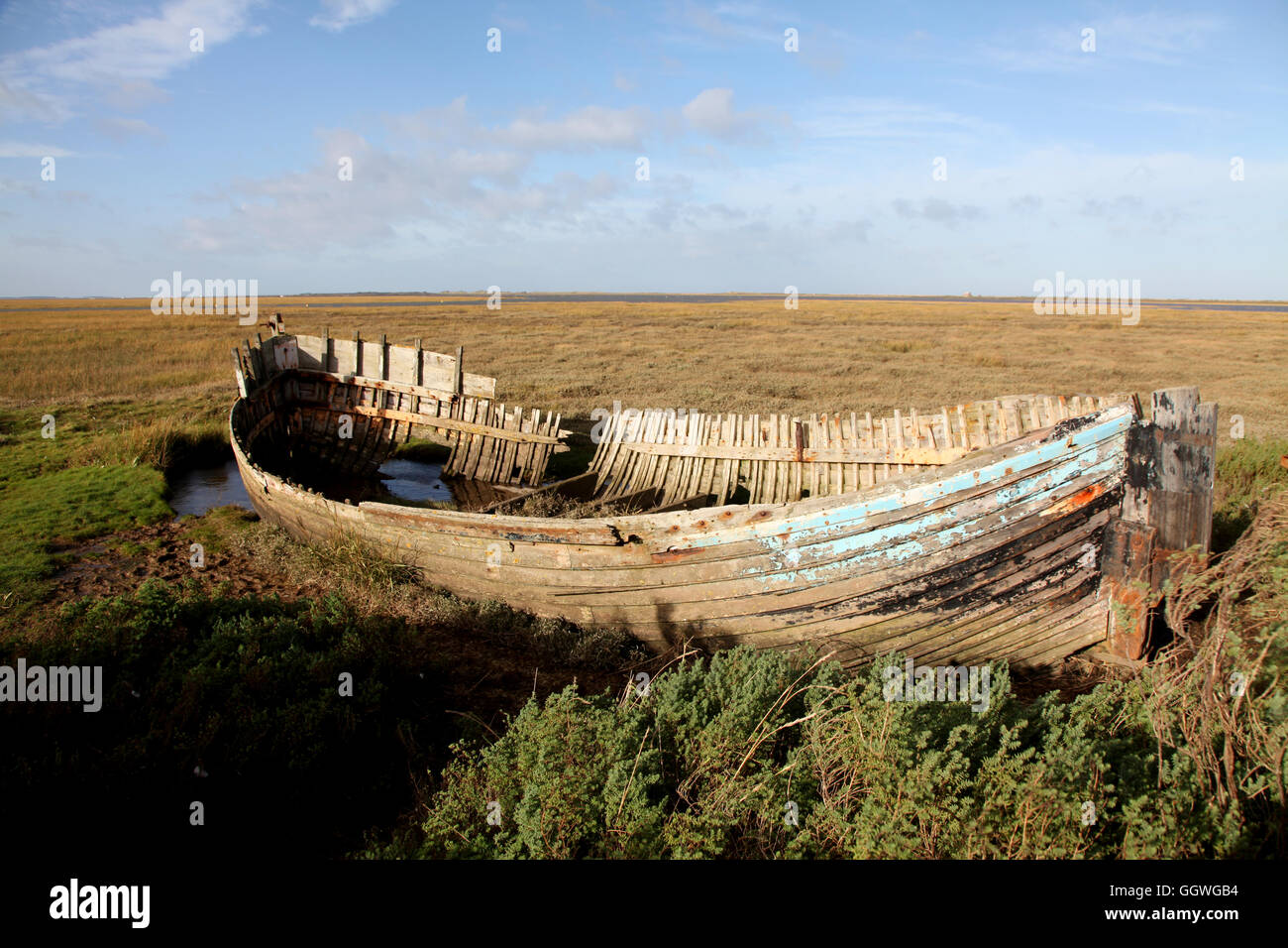An old wrecked whaler lies in the saltmarshes in East Anglia, England amongst a bleak and empty landscape Stock Photo