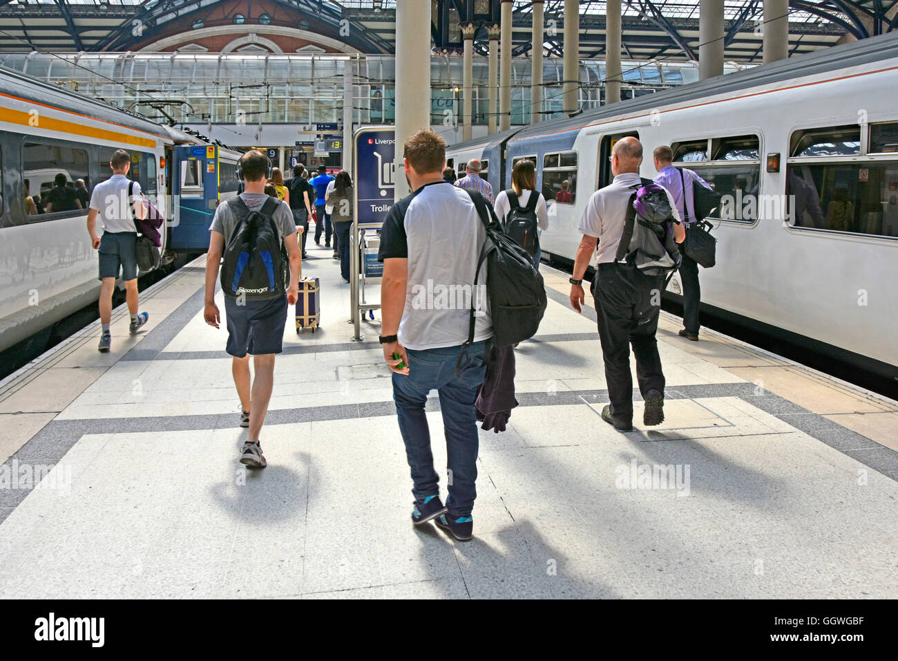 Male public transport train passengers back view Abellio Greater Anglia trains arriving at City of London Liverpool Street UK train station platform Stock Photo