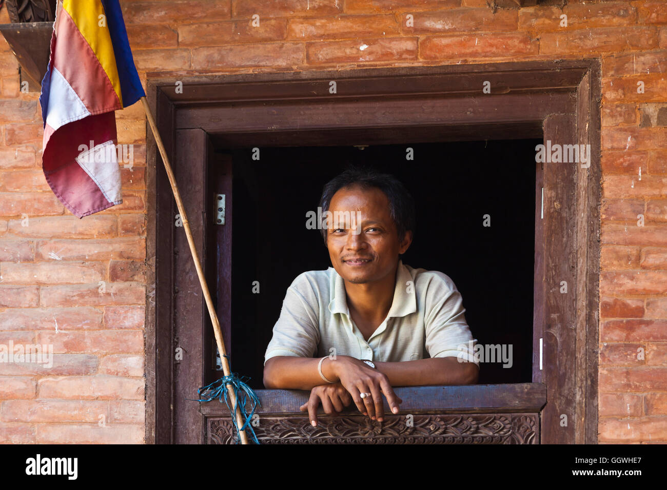 Man in a window in BHAKTAPUR which was severely damaged by the 2015 earthquake - NEPAL Stock Photo