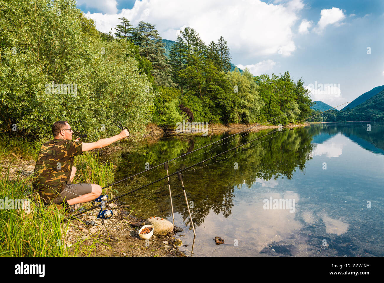 Fishing adventures. Fisherman while groundbait with boilies, using a slingshot fishing Stock Photo