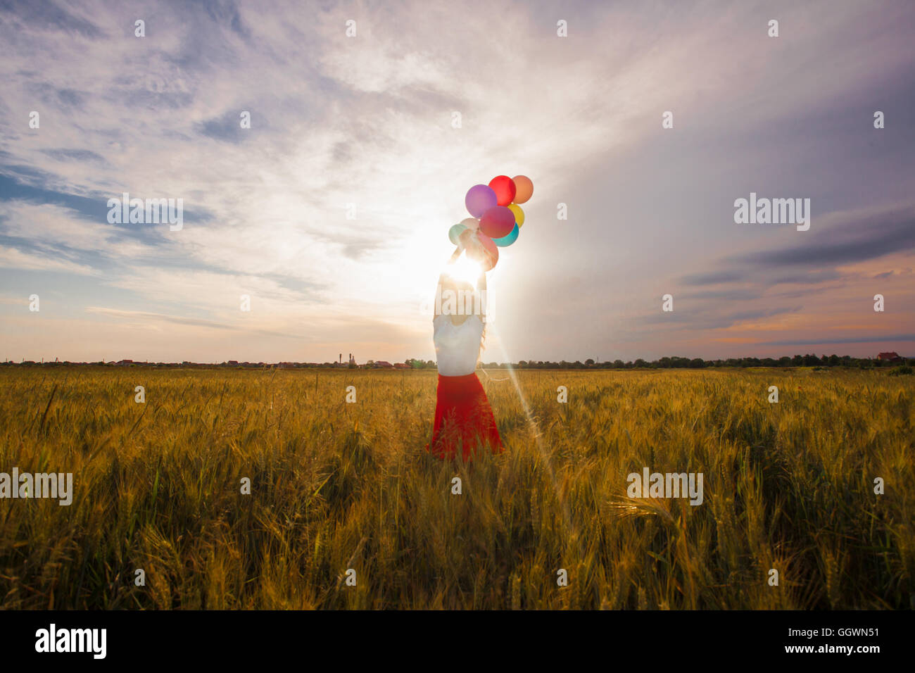 Girl with balloons in wheat field Stock Photo - Alamy