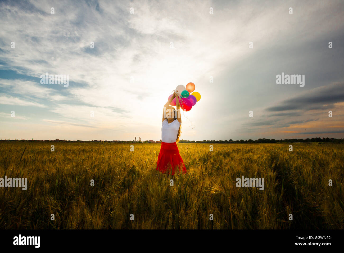 Girl with balloons in wheat field Stock Photo - Alamy