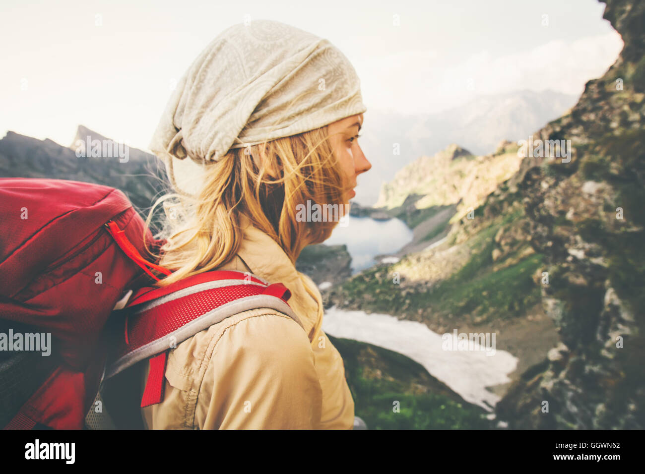 Young Woman with red backpack hiking alone Travel Lifestyle concept lake and mountains landscape on background Summer vacations Stock Photo