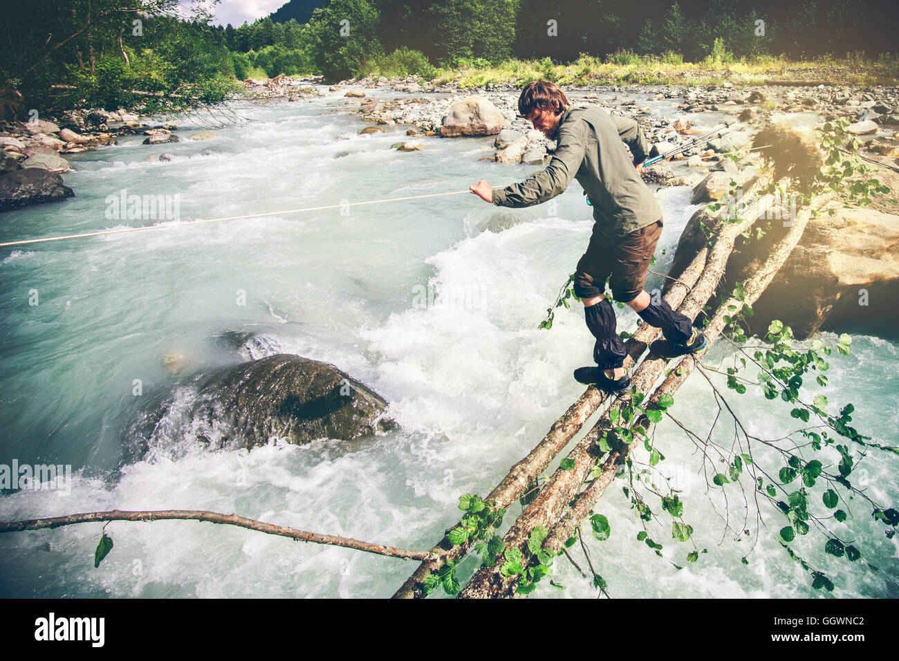 Man Traveler crossing over river on woods outdoor Lifestyle Travel extreme survival concept Stock Photo