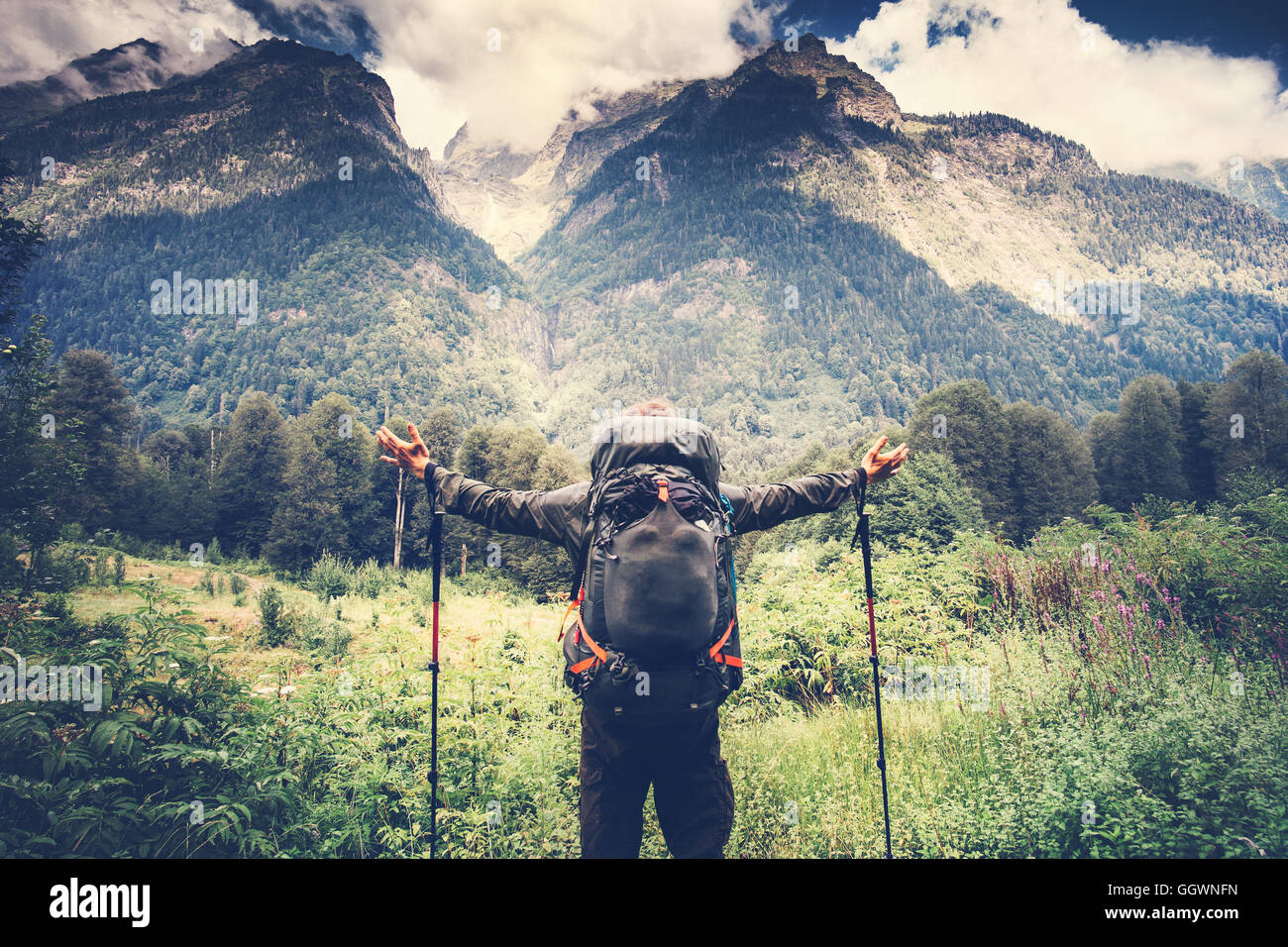 Happy Man with backpack hands raised mountaineering Travel Lifestyle concept beautiful mountains with clouds sky landscape on ba Stock Photo