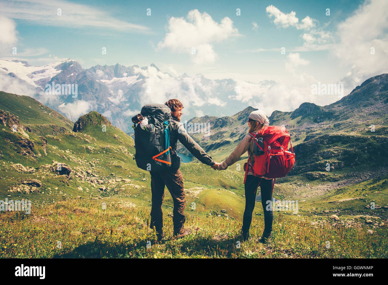 Couple Man and Woman with backpack holding hands mountaineering Travel Lifestyle summer vacations concept mountains and clouds l Stock Photo