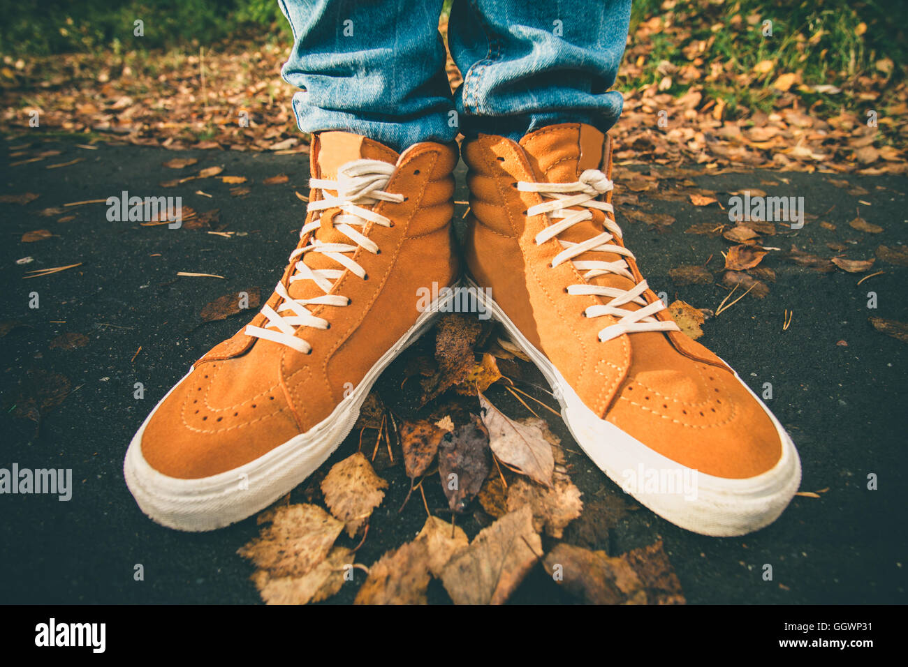 Feet sneakers walking on fall leaves Outdoor with Autumn season nature on background Lifestyle Fashion trendy style Stock Photo