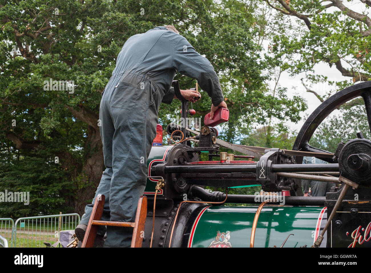 BOCONNOC, CORNWALL, ENGLAND, UK - JULY 31, 2016: Man Pouring Oil into Old Industrial Steam Engine. Historic Heritage Concept. Stock Photo