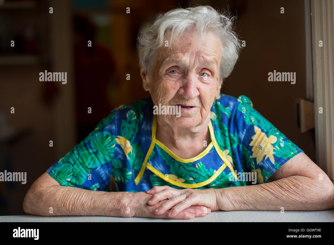 Portrait of an elderly woman sitting at the table. Stock Photo