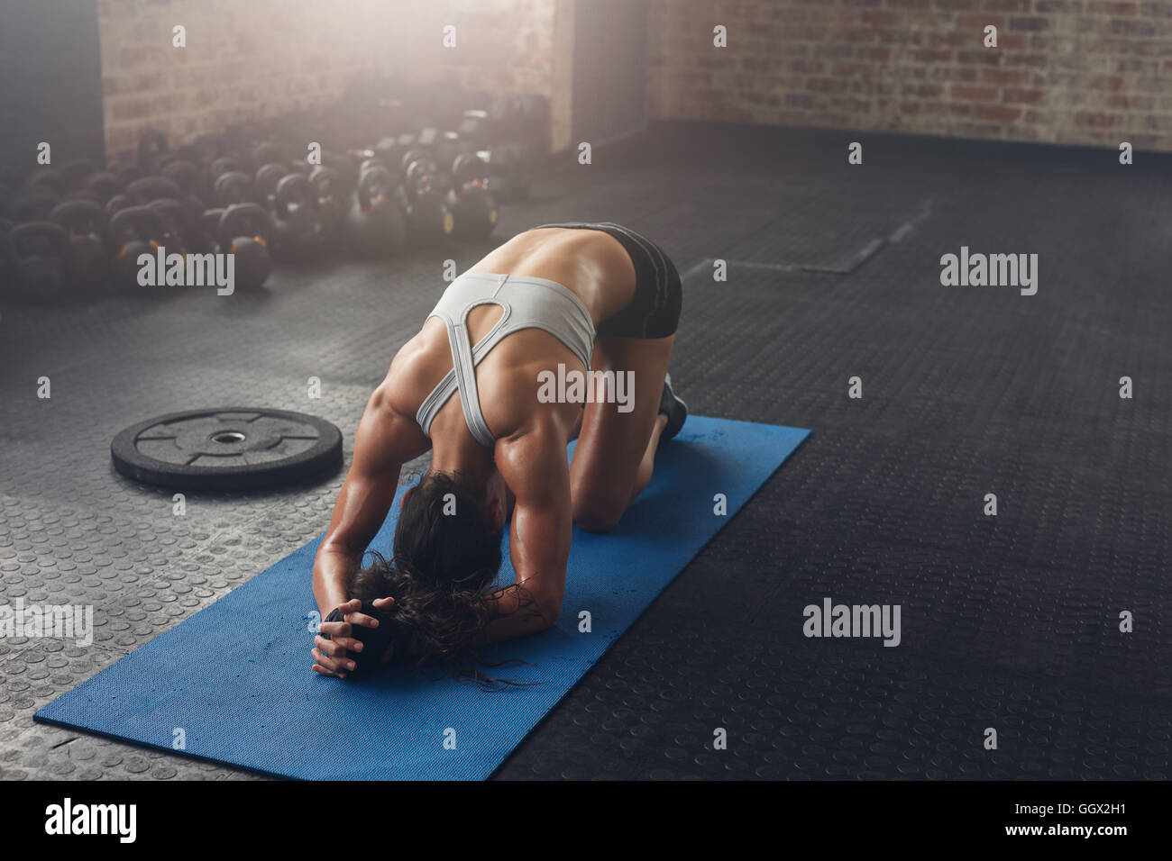 Indoor shot of young woman doing a forward bend exercise on fitness mat. Fit young woman doing pilates workout at the gym. Stock Photo