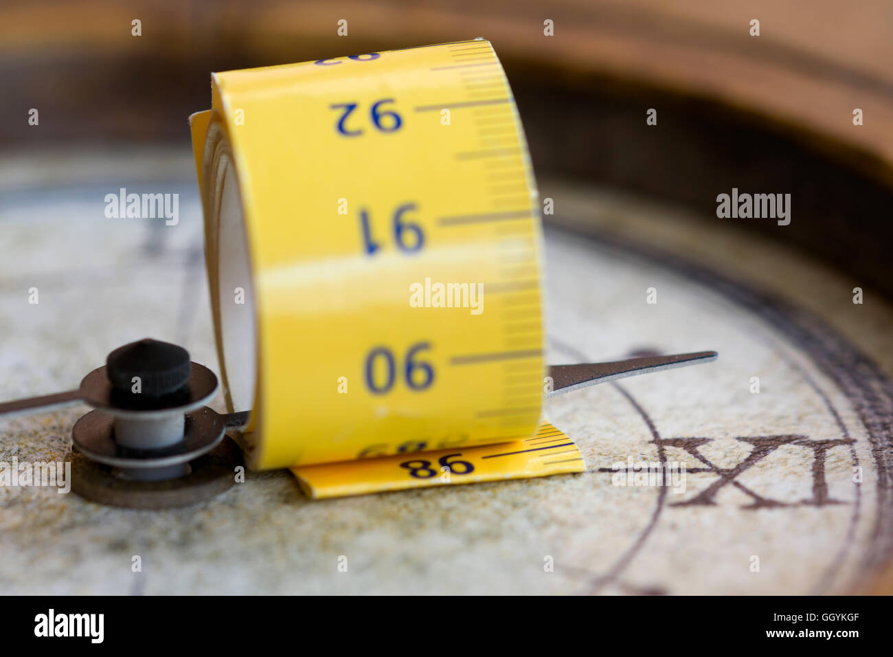 tapemeasure wrapped around at a hands of an old clock. Time measure