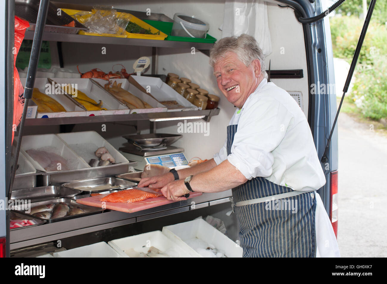 Friendly smiling man serving fresh fish from a mobile van.  A sole trader small business in Wales. Stock Photo