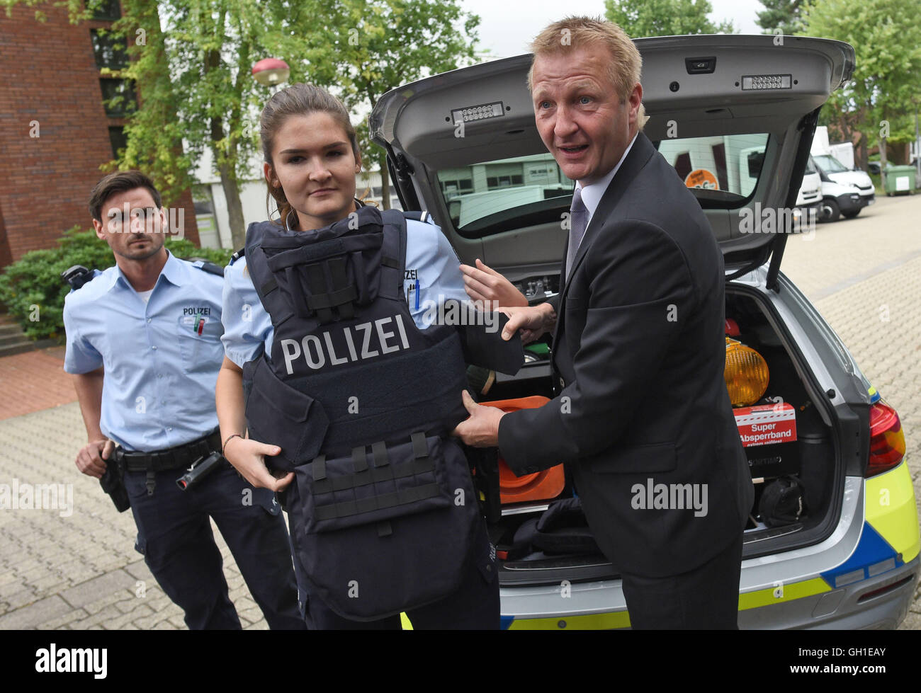 Cologne, Germany. 8th Aug, 2016. Two police officers and Minister of the Interior in North Rhine-Westphalia Ralf Jaeger (SPD, r) presenting the new protective vest during a press call in Cologne, Germany, 8 August 2016. The new vests are said to even withstand bullets shot by automatic weapons. PHOTO: HENNING KAISER/dpa/Alamy Live News Stock Photo