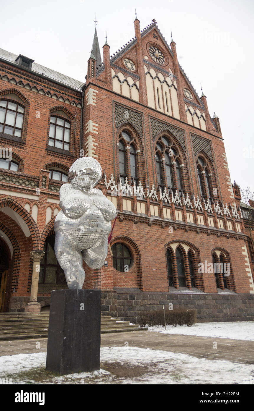 Riga, Latvia - January 1, 2016: The brick gothic building of Academy of Art in Riga, with woman statue from mirror pieces. Stock Photo