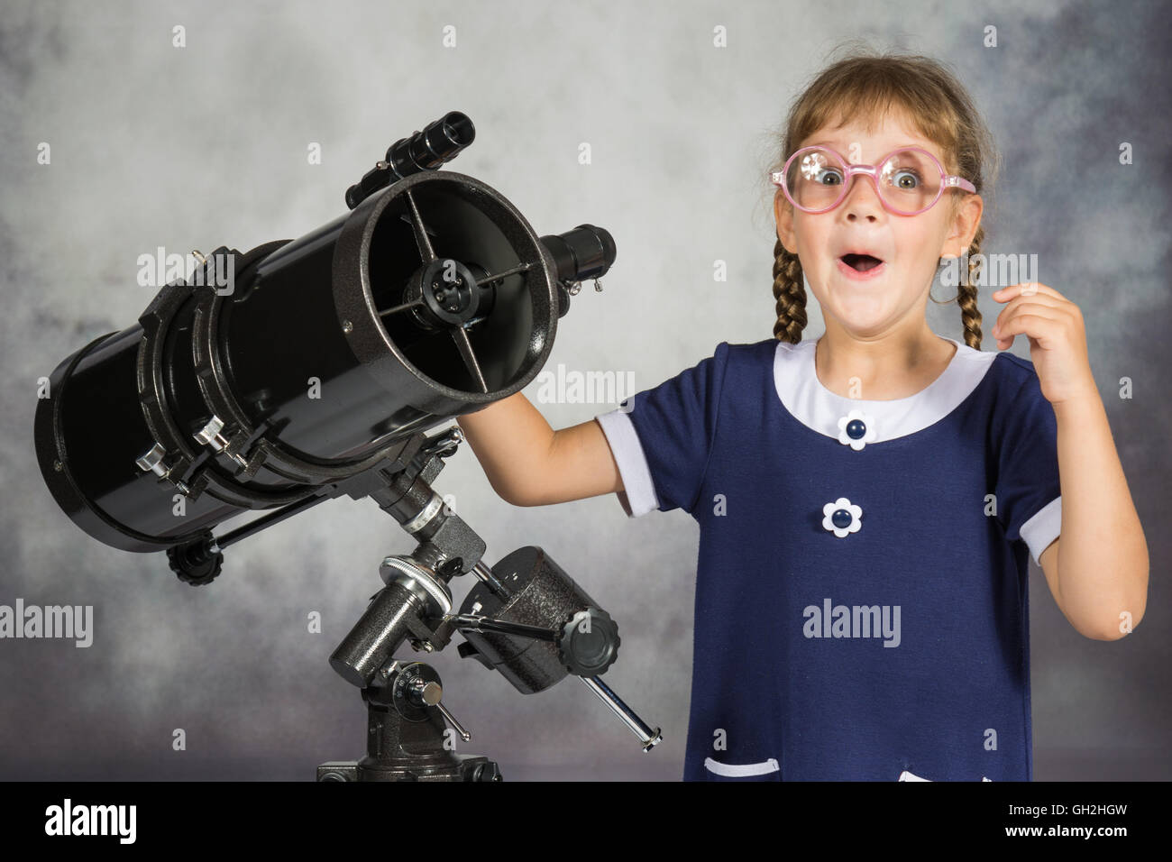 Girl astronomer happily surprised by what he saw in the telescope Stock Photo