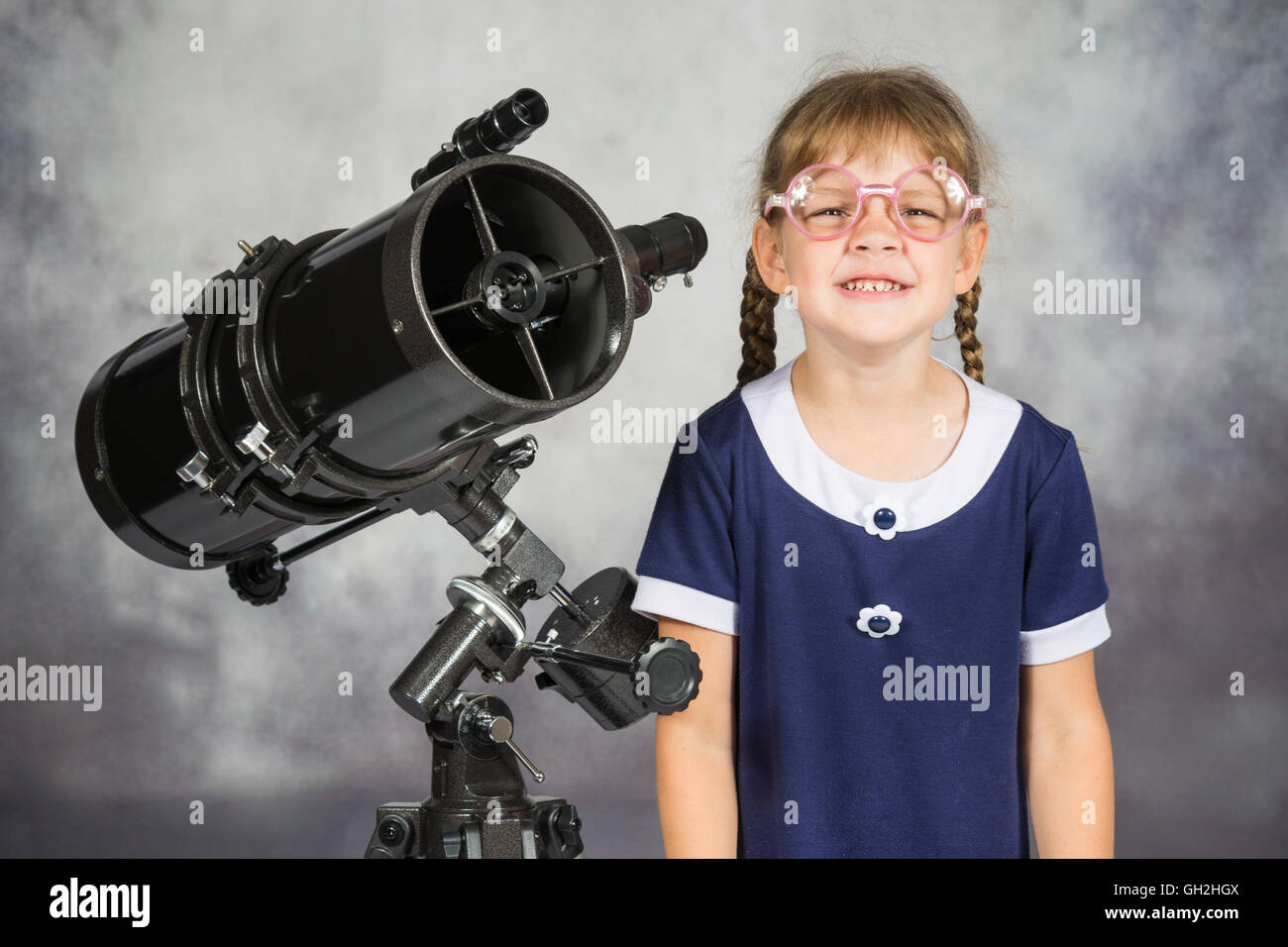 Girl bespectacled amateur astronomer funny smiling standing by telescope Stock Photo