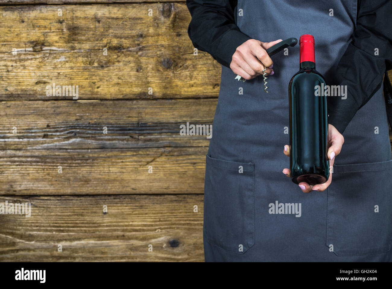 waitress in apron with corkscrew and red wine bottle Stock Photo Alamy