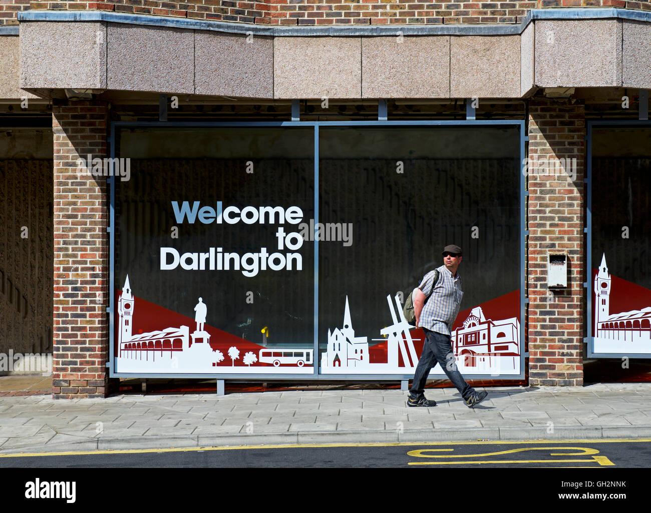 Man walking past sign - Welcome to Darlington - County Durham, England UK Stock Photo