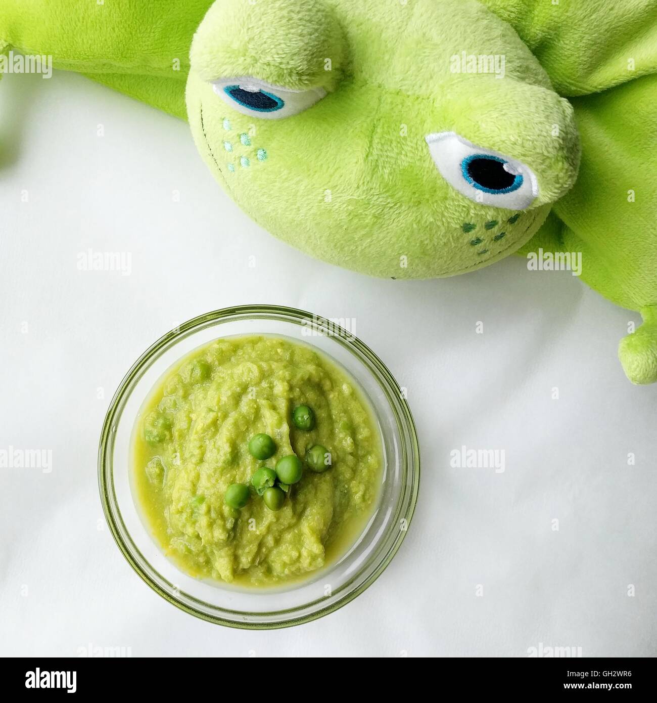 Green baby puree and toy frog Stock Photo