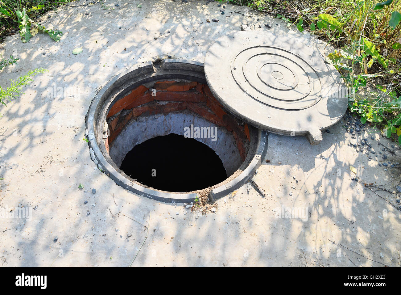 Concrete cesspit with an open hatch on the ground in the summer. Stock Photo