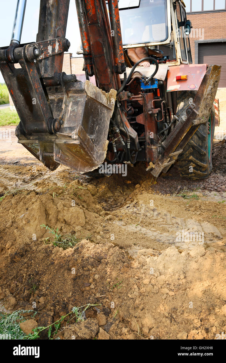 Excavator bucket digging a trench in the dirt ground Stock Photo - Alamy