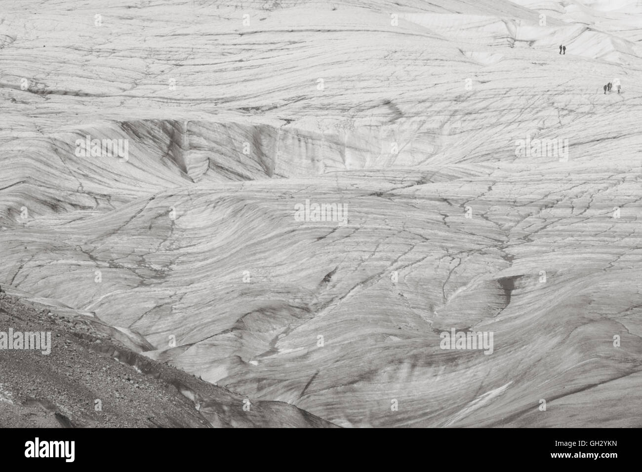Two groups of people walk across the vastness of the leading edge of the Root Glacier in Eastern Alaska. Stock Photo