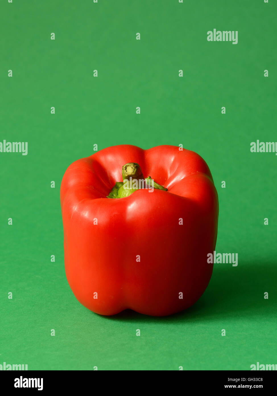 Red Bell pepper on a green background Stock Photo - Alamy