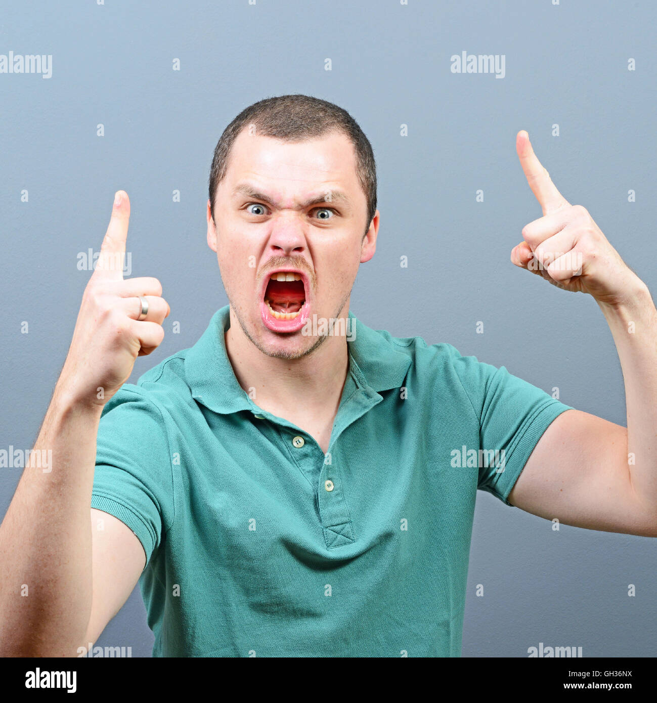 Portrait of a angry threatening man screaming against gray background Stock Photo