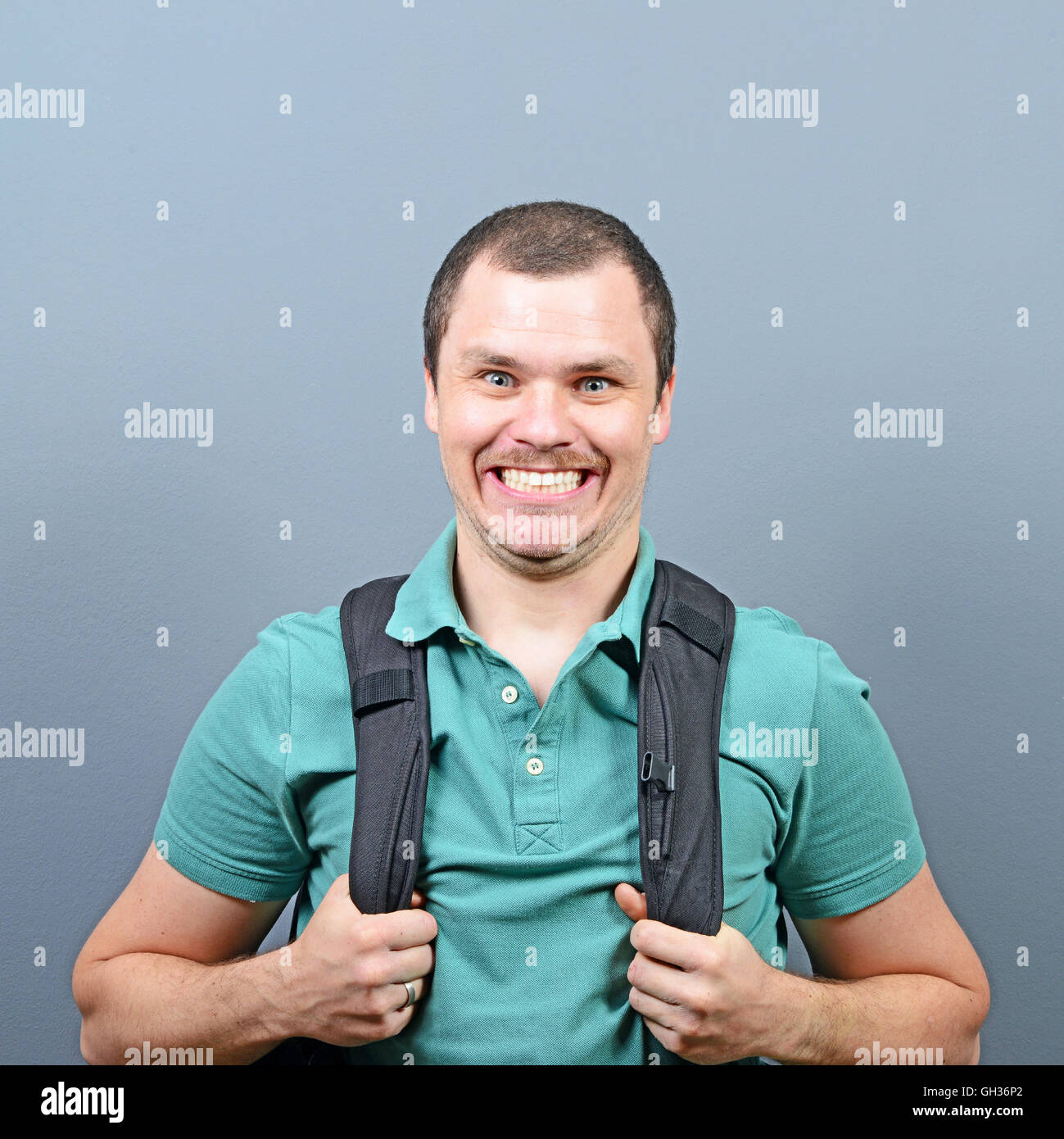 Portrait of a funny man with backpack against gray background Stock Photo