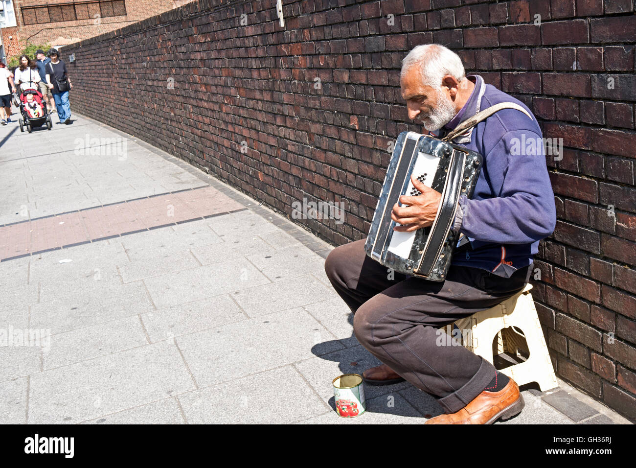 An elderly street busker plays an accordion for money on the streets of London Stock Photo