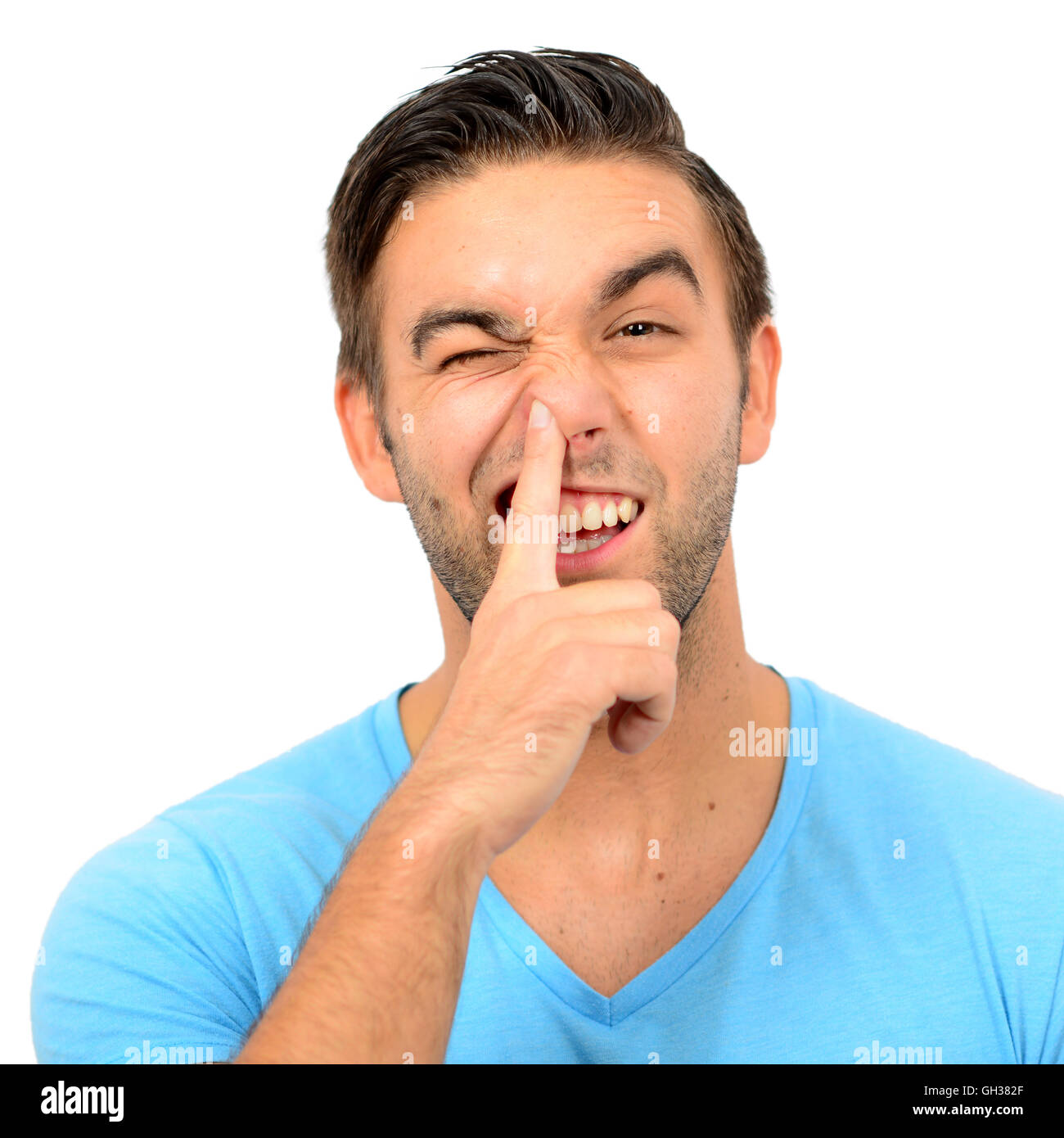 Portrait of a funny guy with finger in his nose against white