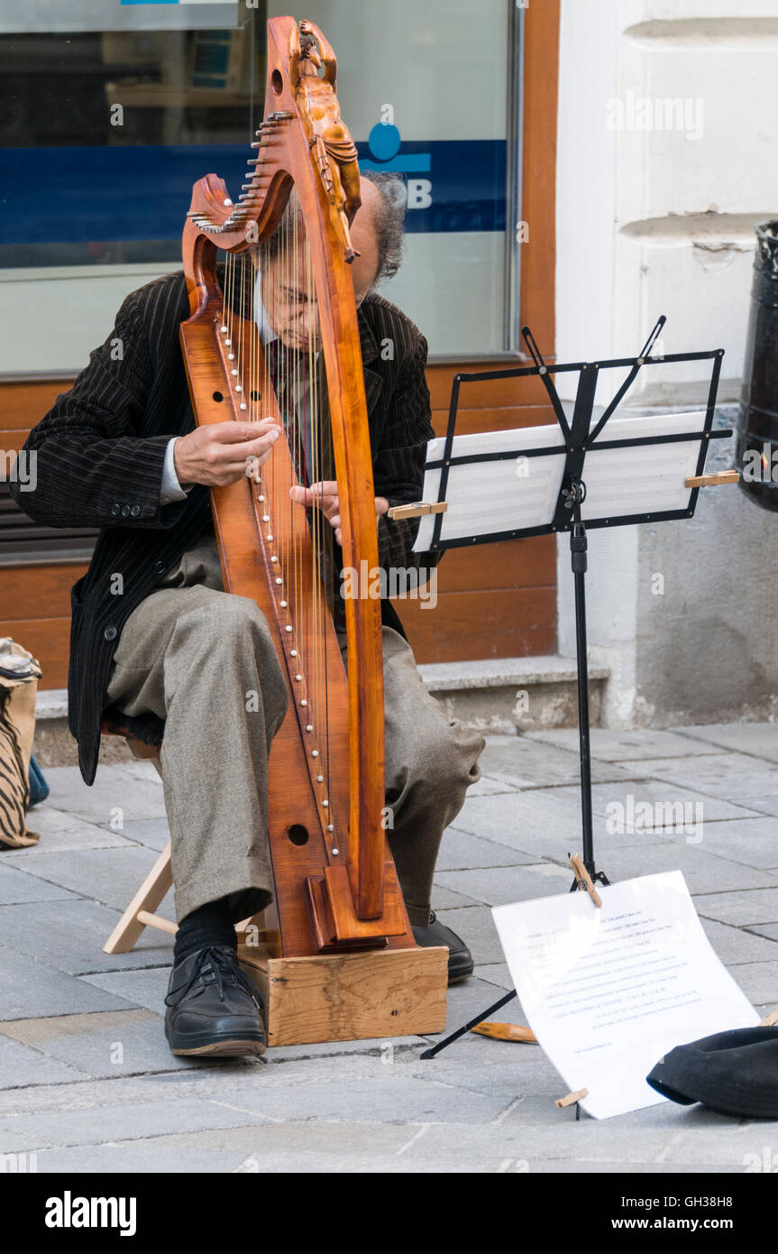 A street busker playing his harp in Bratislava old town in Slovakia Stock Photo