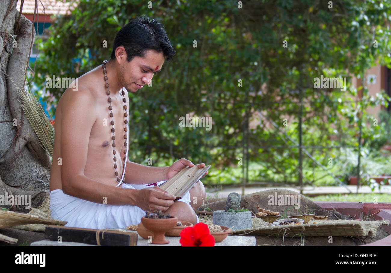 A young traditional ayurvedic doctor reading an ancient palmleaf