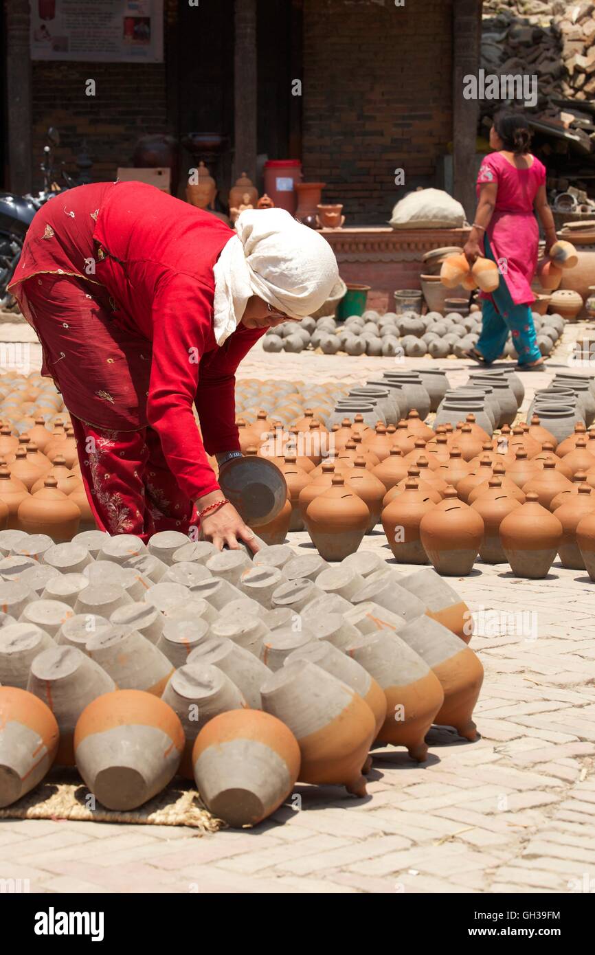 Woman turning pots to dry in sunshine, Potter's Square, Bhaktapur, Nepal, Asia Stock Photo