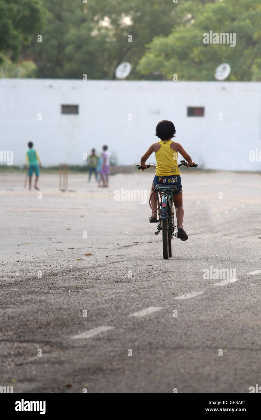 A small Indian girl riding away on her bicycle Stock Photo
