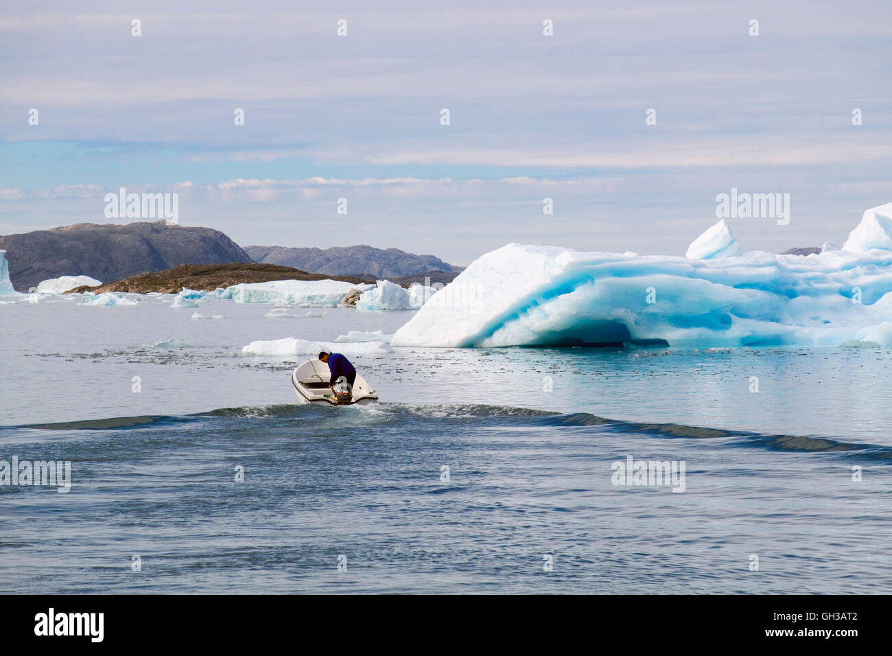 Local Inuit fisherman sailing a small fishing boat amongst icebergs in Narsaq Sound. Narsaq Kujalleq Southern Greenland Stock Photo