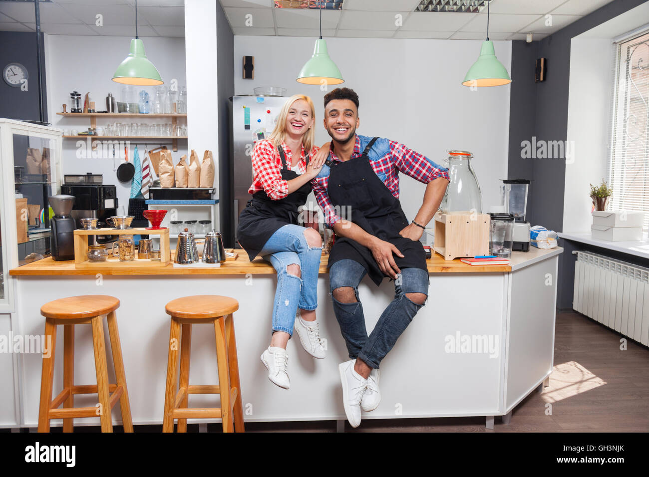 Barista coffee shop owner couple happy smile sitting on bar counter Stock Photo