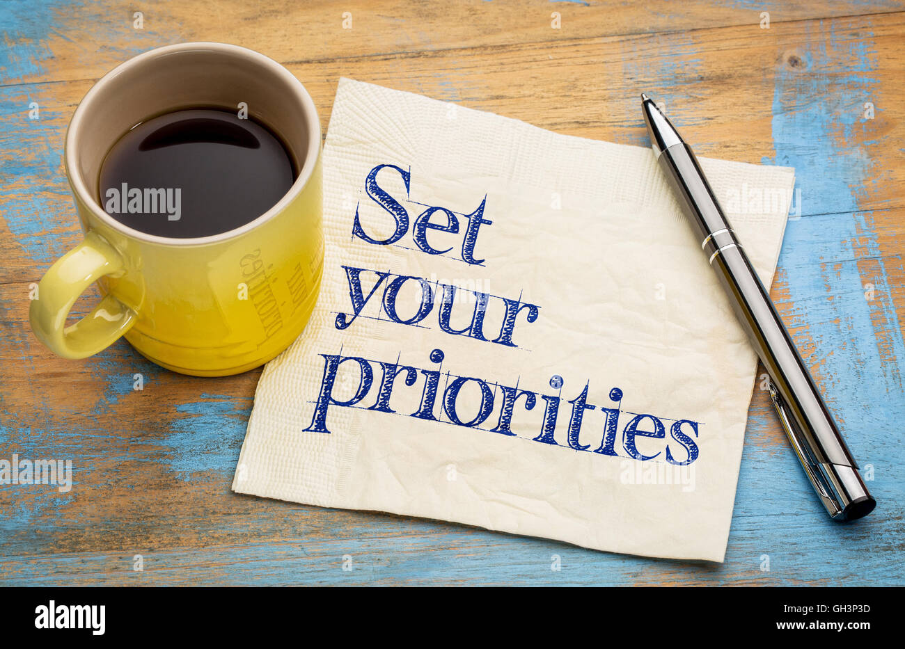 Set your priorities reminder - handwriting on a napkin with a cup of espresso coffee Stock Photo