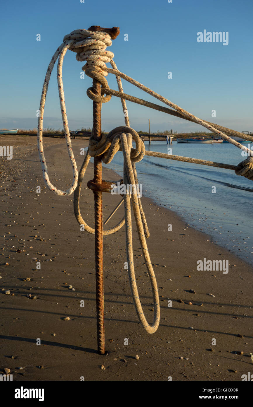 A rope of a boat is tie up with iron stake on the beach Stock Photo