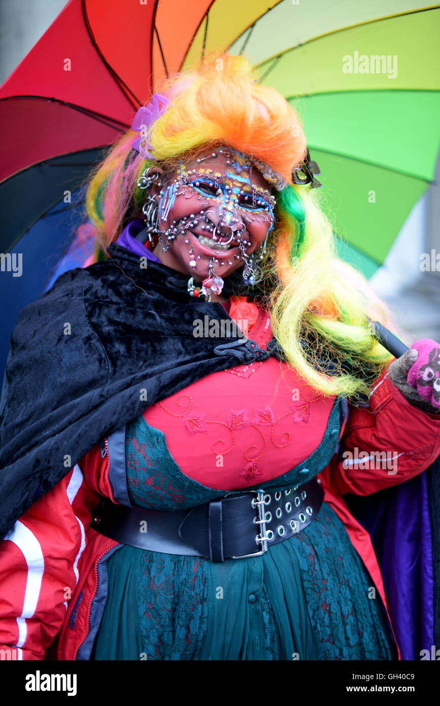 Street performer with lots of piercings, colorful dress. Stock Photo