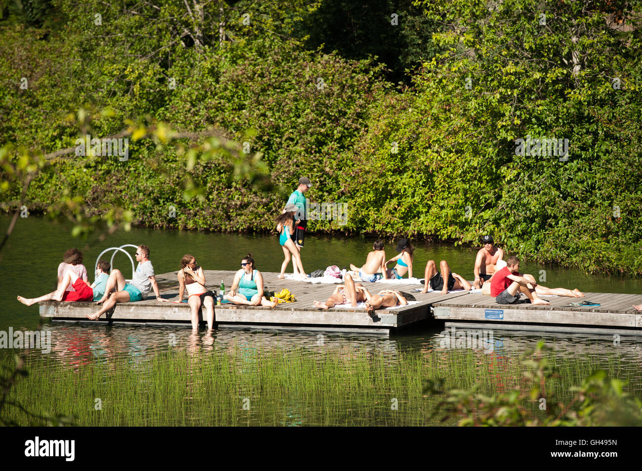 Sun bathers on the dock at Nita Lake.  The Nita Lake Lodge, Summer, Whistler BC, Canada Stock Photo