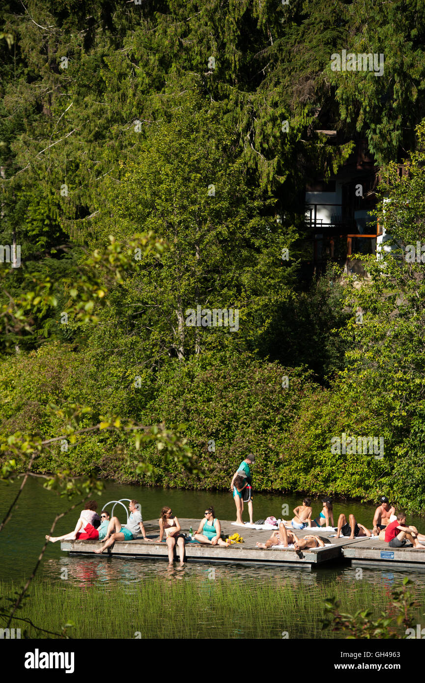 Sun bathers on the dock at Nita Lake.  The Nita Lake Lodge, Summer, Whistler BC, Canada Stock Photo