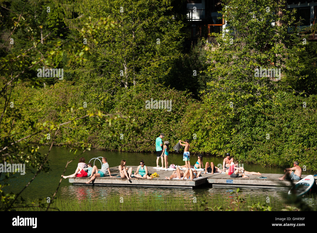 Sun bathers on the dock at Nita Lake.  The Nita Lake Lodge, Summer, Whistler BC, Canada Stock Photo