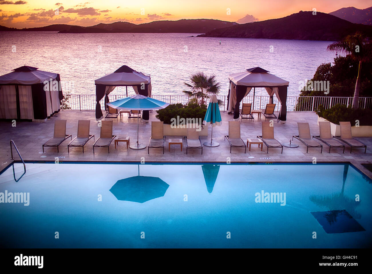 High Angle View of a Pool with Lounge Chairs and Parasols, Overlooking a Bay at Sunset, Charlotte Amalie, St Thomas, US Virgin I Stock Photo