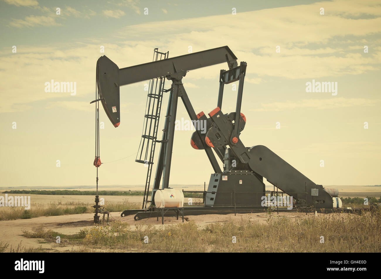 Pump jack starting the lifting stroke to brink crude oil up out of a producing oil well. Retro instagram look. Stock Photo